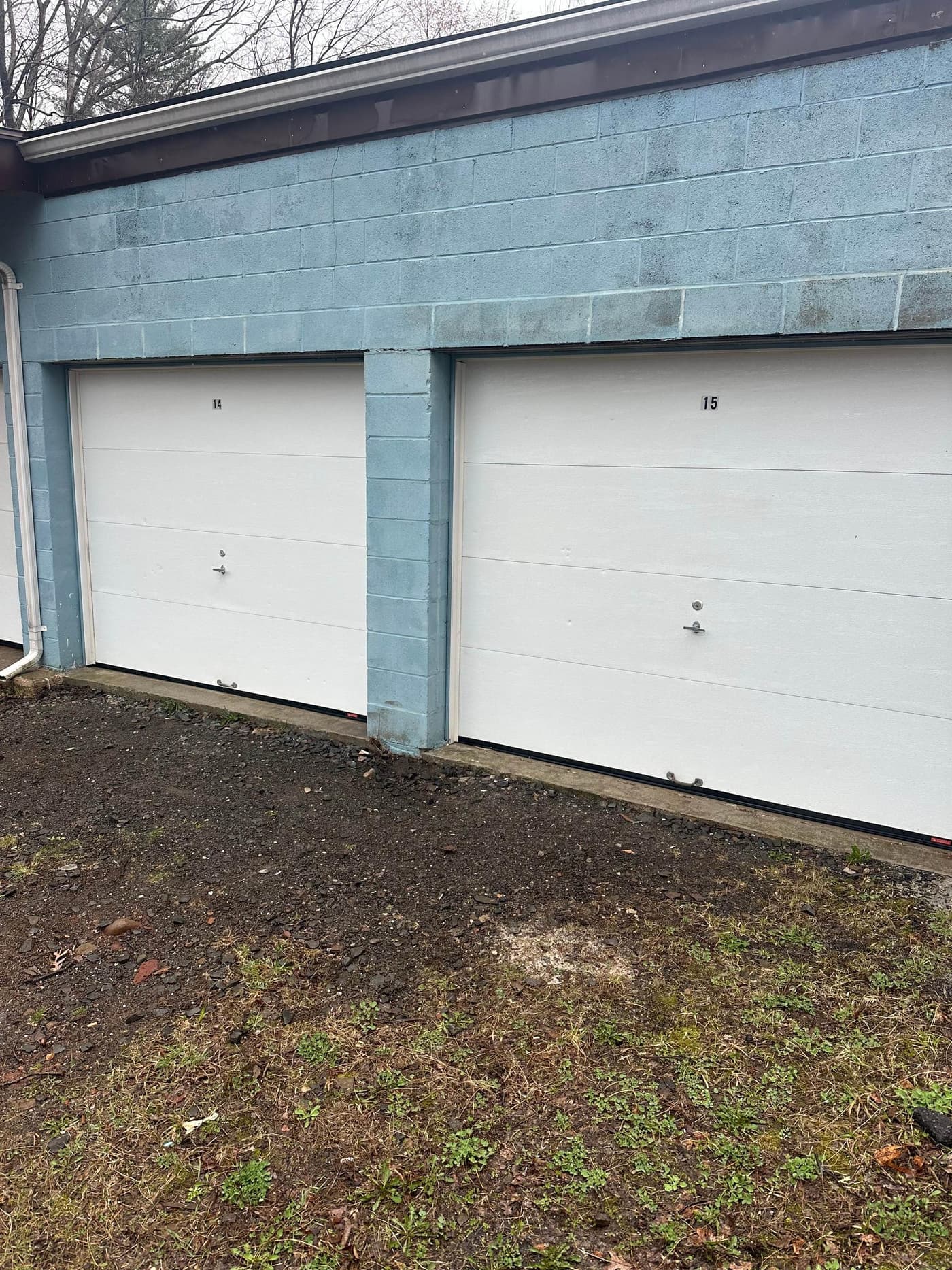 Same commercial garage building after cleaning with bright blue cinder block and white doors