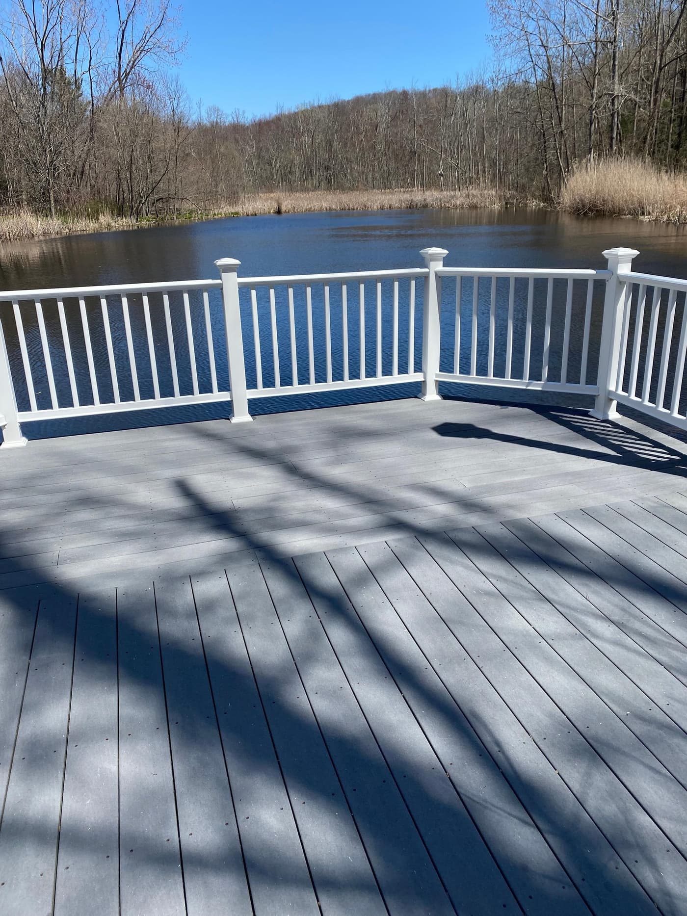 Same lakeside deck beautifully cleaned with white railings overlooking the pond