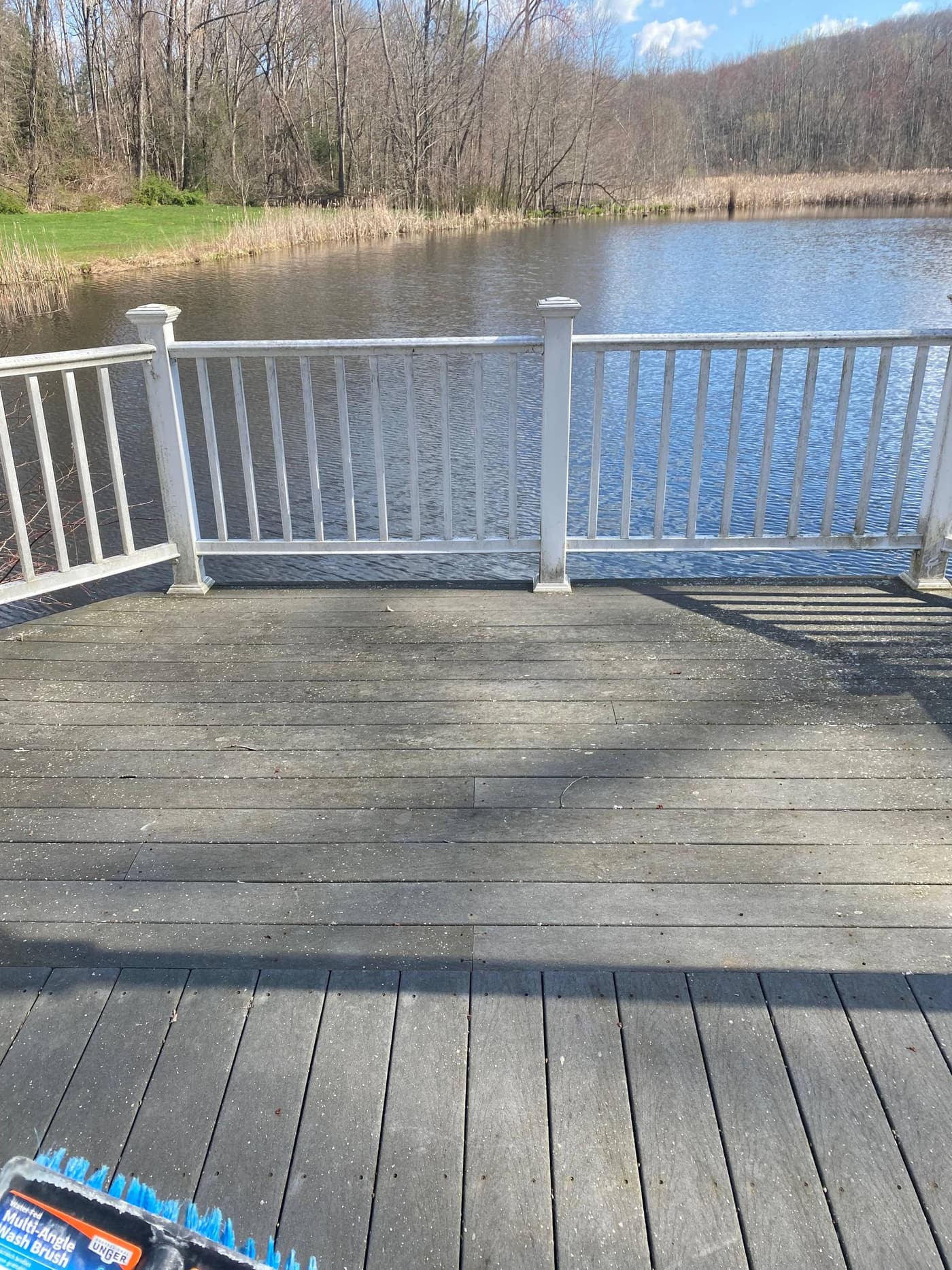 Dirty weathered composite deck overlooking a pond before cleaning